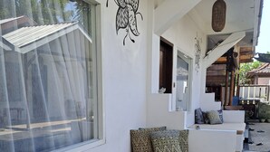 A modern interior with a long bench, a potted plant, and a wall mural. - Katara Gili Boutique Rooms and Bungalows (Gili Trawangan)