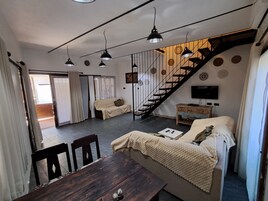 Un espacio habitable moderno con comedor, sofá, escalera y televisor.