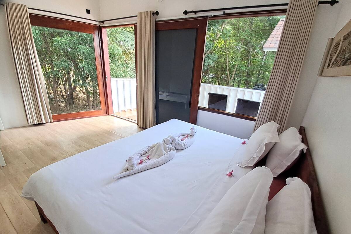Ein Hotelzimmer mit Bett, großem Fenster und Blick ins Grüne.