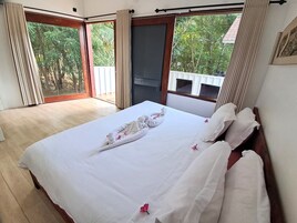 Habitación de hotel con cama, ventana grande y vistas al verdor.