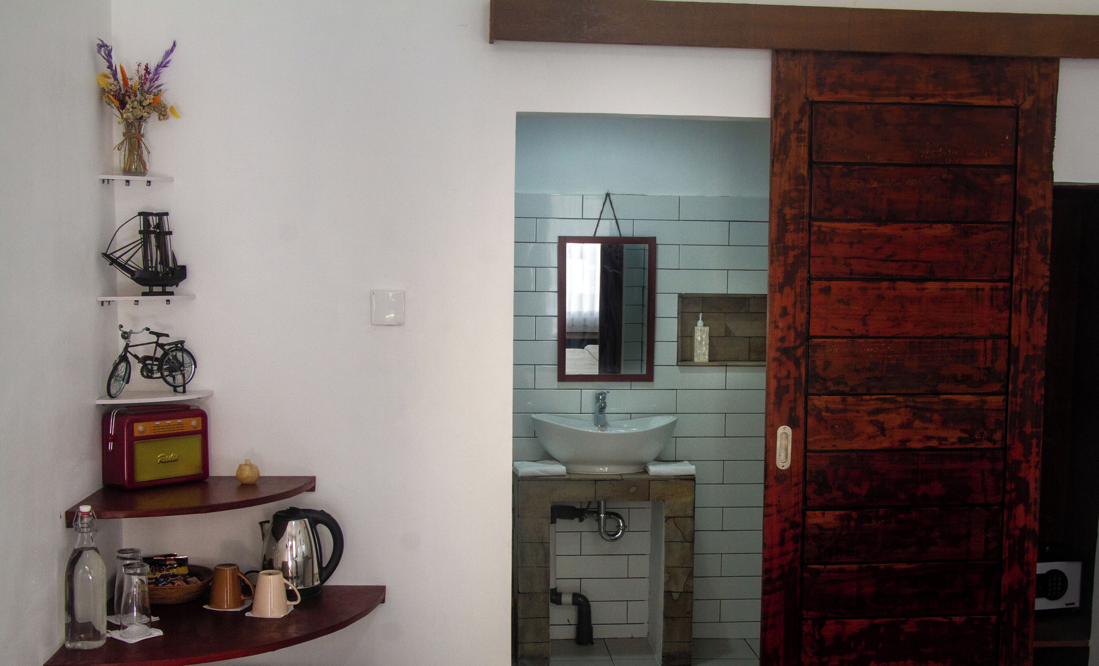 Een badkamer met een wastafel, spiegel en een houten deur.
