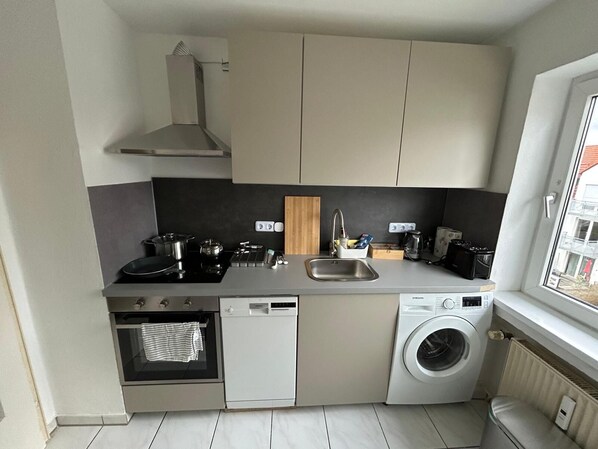 A compact kitchen with a stove, oven, dishwasher, and washing machine.