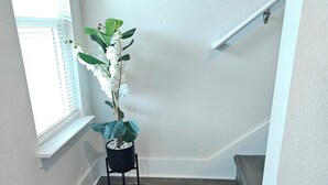 A staircase with dark wooden steps, a potted plant, and a window with blinds. - Walk to Beach | Family-Friendly 3BR Home w/ Garage (Biloxi)