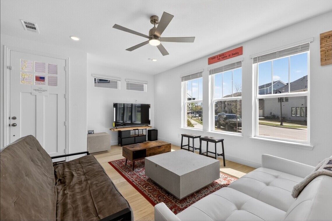 Un salon moderne doté d’un ventilateur de plafond, d’un téléviseur à écran plat, d’une table basse et d’un canapé.
