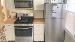 A compact kitchen with a microwave, stove, oven, and refrigerator, featuring white cabinetry and a patterned floor. - The perfect blend of space and comfort in Providence, RI. (Providence)