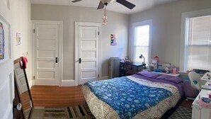 A bedroom with a bed, a desk, a chair, a radiator, and a window. - The perfect blend of space and comfort in Providence, RI. (Providence)
