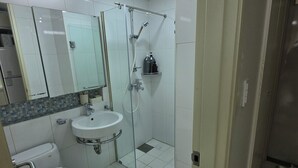 Un bagno con lavandino bianco, uno specchio, cabina doccia in vetro e un water.