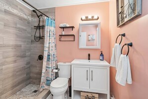 Un bagno con doccia, wc, lavandino e porta asciugamani.