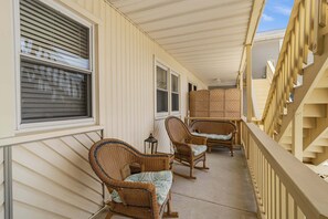 Eine überdachte Veranda mit Korbmöbeln und einem Holzbalkon.