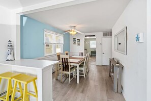 Una cucina moderna con zona pranzo, una ventola a soffitto e un'isola piccola con sgabelli.