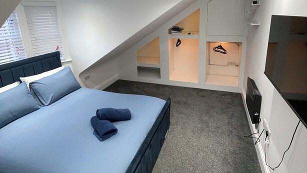 A bedroom with a bed, a TV, and built-in shelving. - Stylish 2BR Duplex - Central & Spacious (Sunderland)