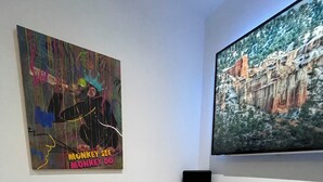 A room with a television mounted on the wall, a colorful abstract painting, and a round bean bag chair. - Stylish 2BR Duplex - Central & Spacious (Sunderland)