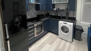 A modern kitchen with a black refrigerator, stainless steel oven, microwave, and washing machine. - Stylish 2BR Duplex - Central & Spacious (Sunderland)