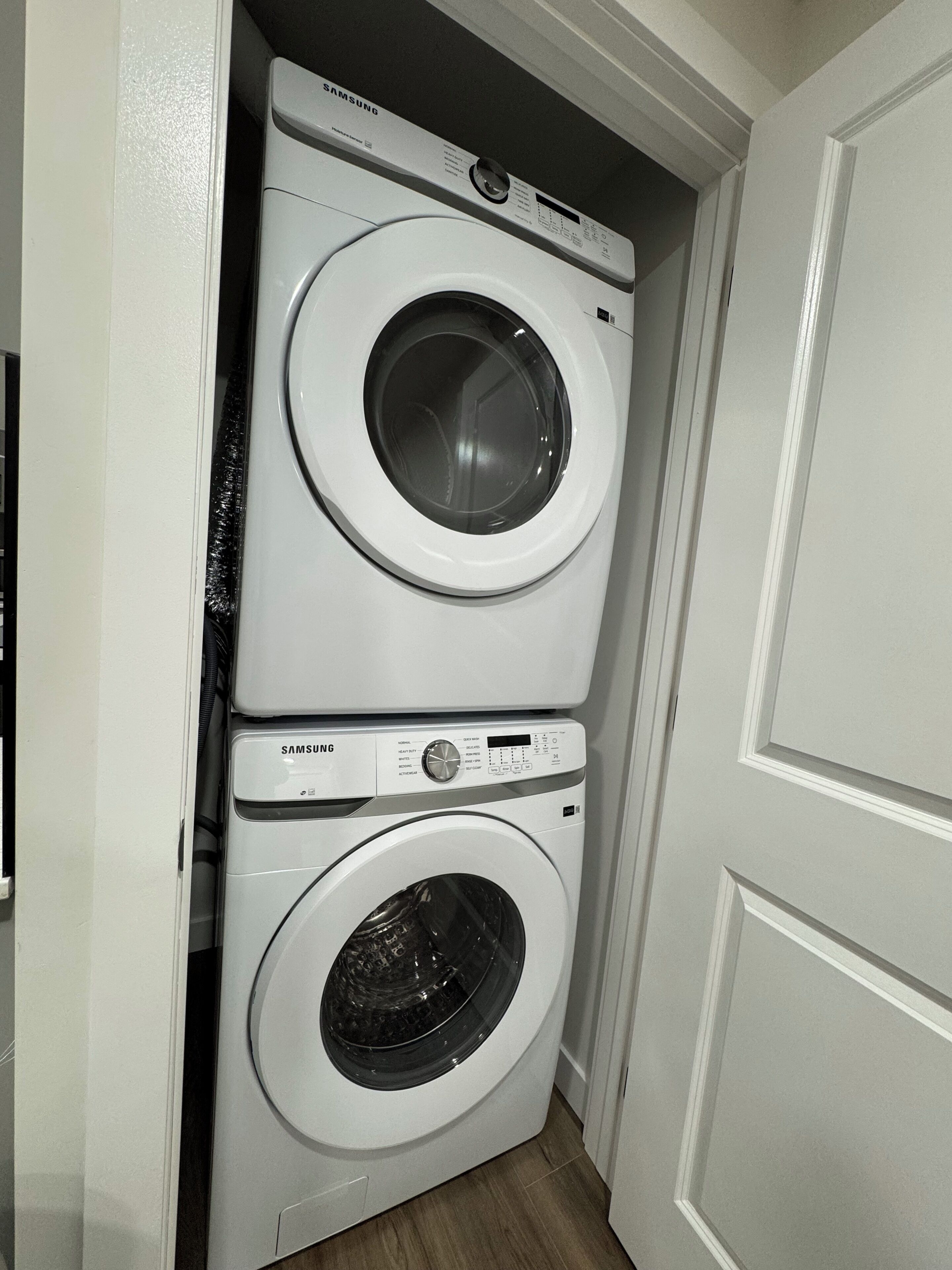 A stacked washer and dryer unit in a hallway.