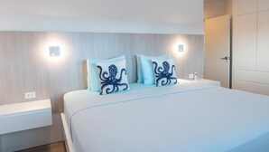 Una habitación de hotel con cama, mesitas de noche, aire acondicionado de pared y una puerta.