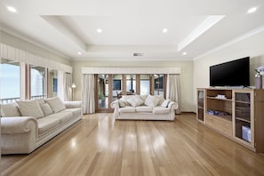 Un salón amplio con un sofá grande, un televisor y un mueble de madera.