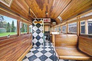 Un wagon de train avec des panneaux de bois, un sol à carreaux et un banc.