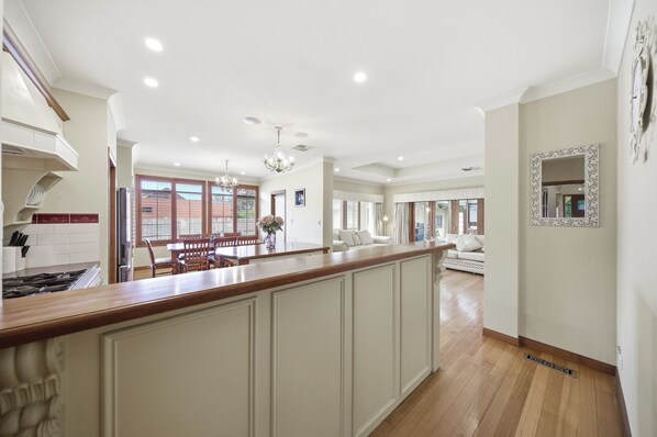 Una cocina amplia con una isla central, suelo de madera y un comedor con un sofá blanco.