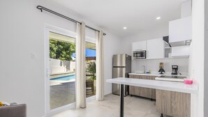 A modern kitchen with a built-in microwave, a stainless steel refrigerator, and a white countertop. - Charming 1BR1BA Getaway/Pool, BBQ &Laundry Access (Oranjestad)