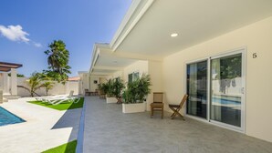 A modern outdoor patio with a pool, lounge chairs, and potted plants. - Charming 1BR1BA Getaway/Pool, BBQ &Laundry Access (Oranjestad)