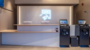 A reception desk with a neon sign, two computers, and a trash bin. - Toyoko Inn Kure-eki (Kure)