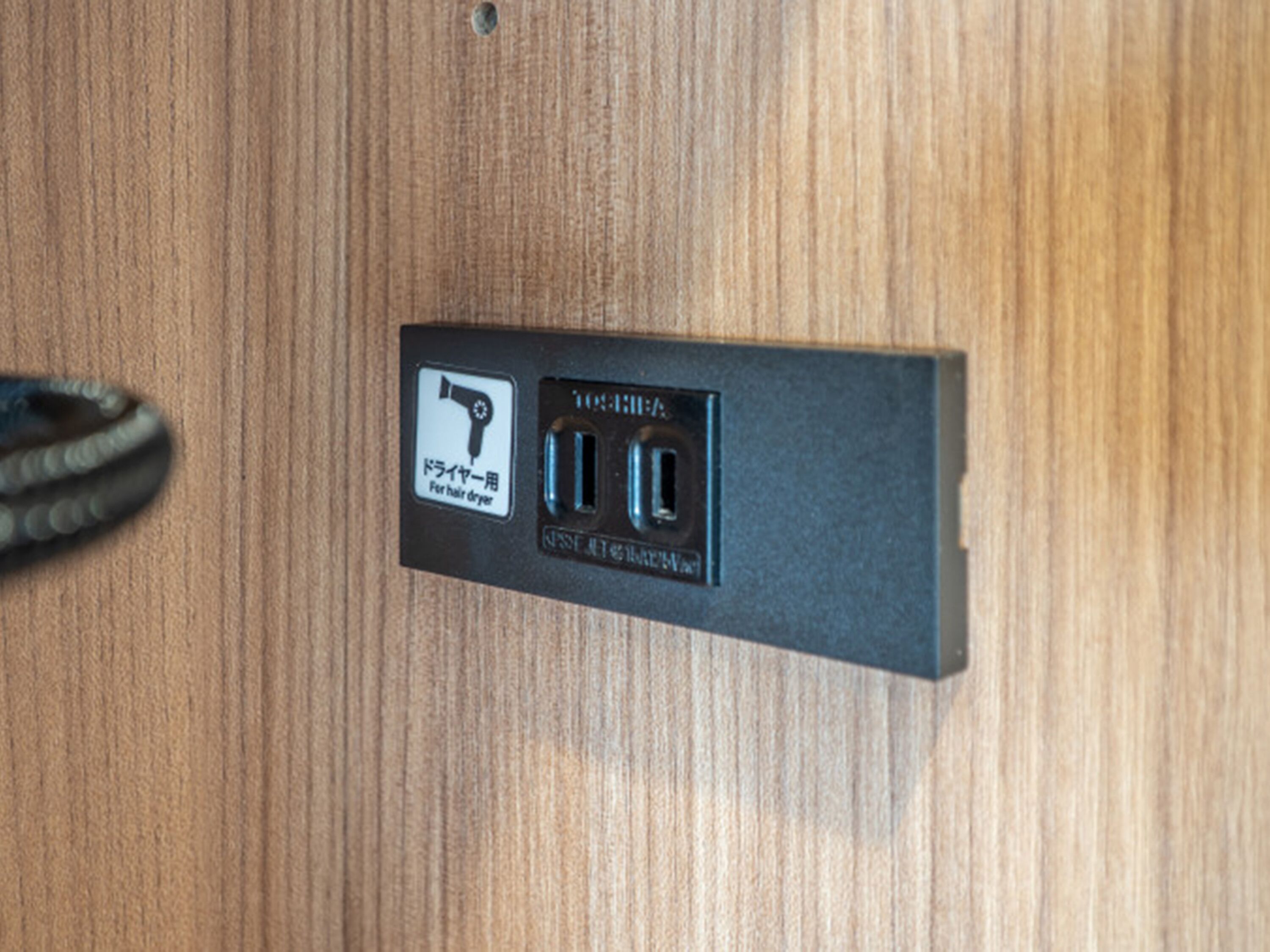 Een wandcontactdoos met een icoon van een haardroger, wat aangeeft dat het een stopcontact voor een haardroger is.
