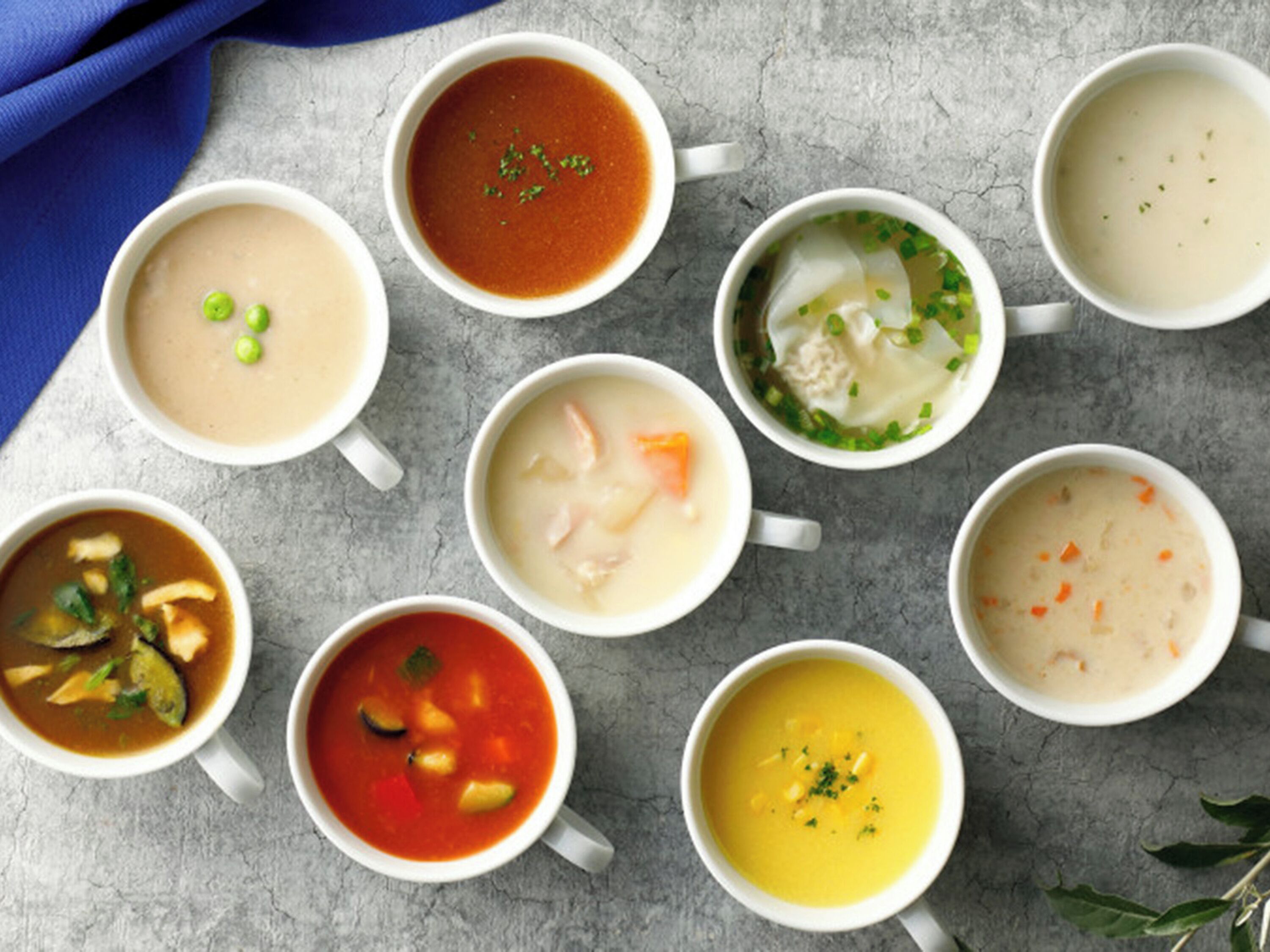 Nine bowls of soup arranged on a table.