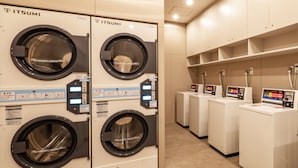 A row of white ITSUMI branded washing machines with control panels, arranged in a clean, tiled laundry room. - Toyoko Inn Kure-eki (Kure)