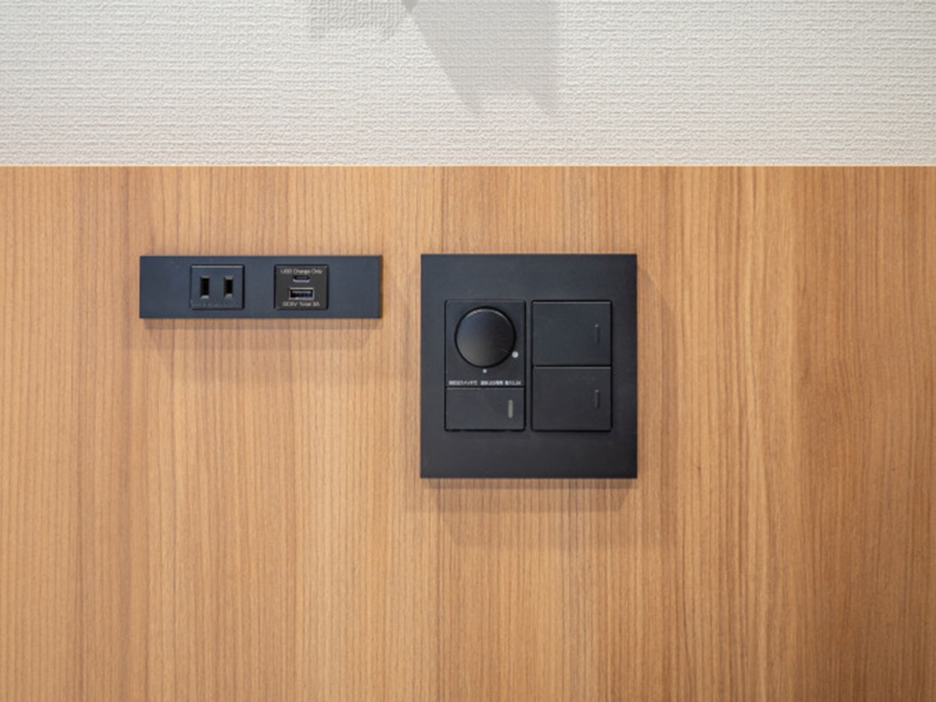 A wall-mounted control panel with a circular dial and two buttons, and a USB charging station with a power outlet.