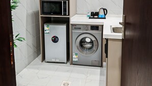 A compact kitchen with a microwave, refrigerator, and washing machine. - Fantastic 1-bedroom apartment with AC in vibrant Jeddah (Jeddah)