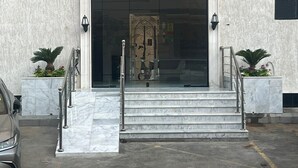 A building entrance with a marble staircase, a glass door, and two potted plants on either side. - Fantastic 1-bedroom apartment with AC in vibrant Jeddah (Jeddah)