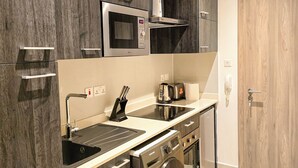 Una cocina compacta con microondas integrado, cafetera, tostadora y lavadora.
