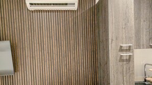 Una cocina moderna con una mesa redonda de madera y dos sillas, un lavamanos empotrado y un aire acondicionado de pared.