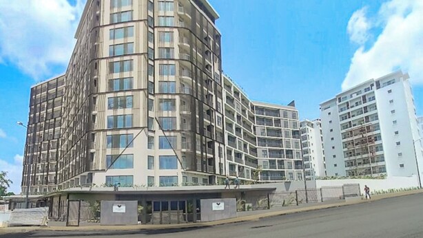 Un hotel de varios pisos con fachada curva, ventanas grandes y un área de entrada cubierta.