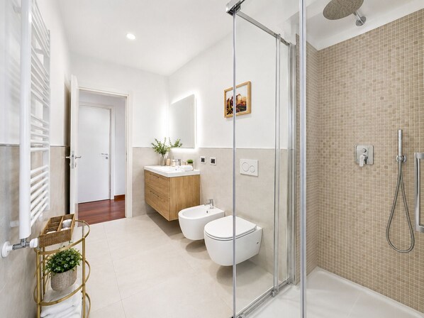 A modern bathroom with a glass shower enclosure, a white toilet, a wooden vanity, and a white sink.