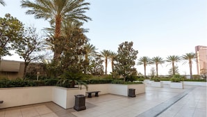Un vaste espace extérieur agrémenté de palmiers, de jardinières et doté d’un sol carrelé.