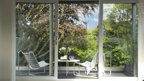 A modern room with large glass doors, a white table with chairs, and a view of trees. - Estuary Watch - River view, Pets welcome, Family Friendly (Lelant)