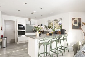 Una cocina moderna con una isla central, taburetes de bar y un ventanal con vistas.
