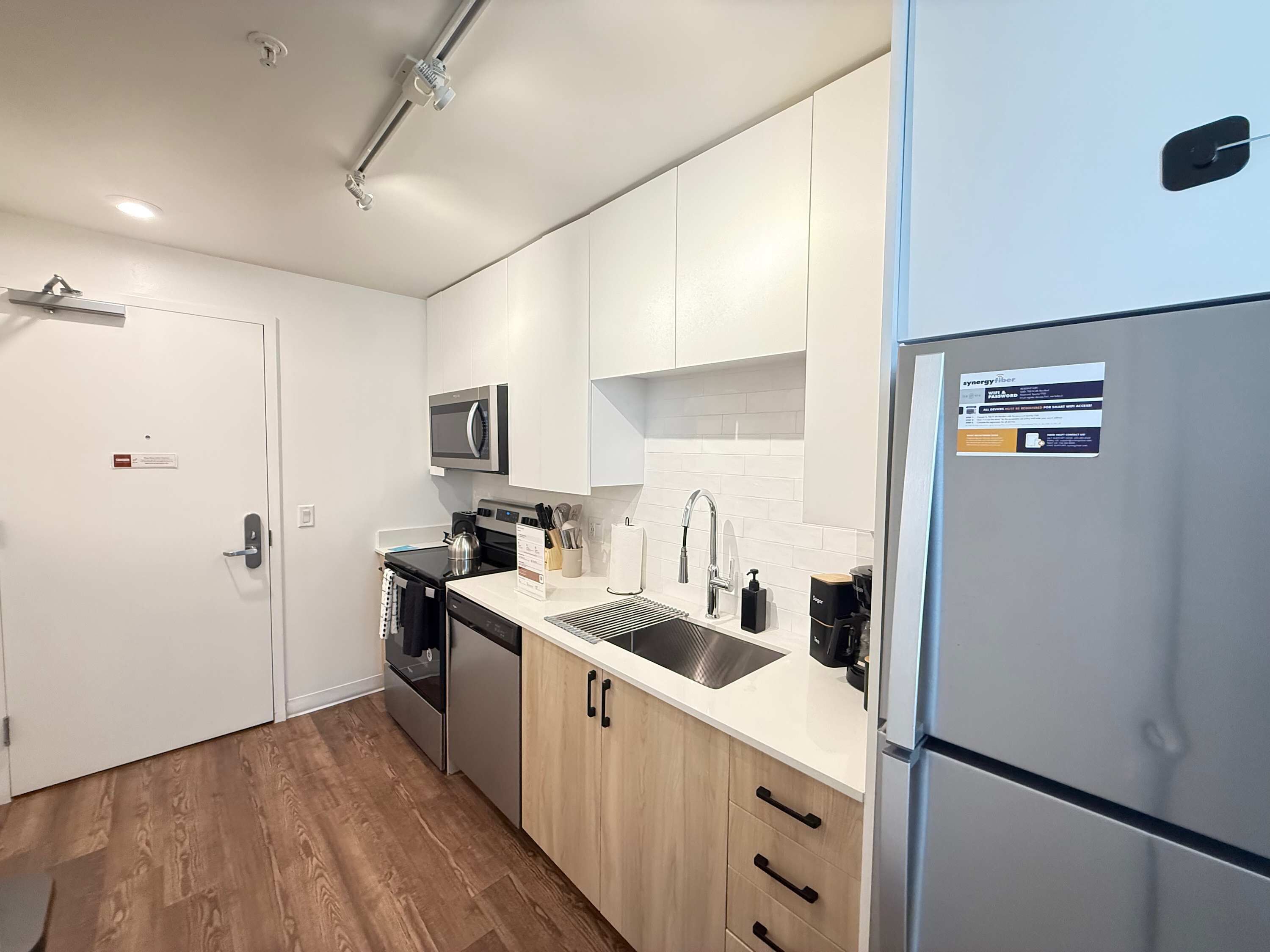 A modern kitchen with white cabinets, stainless steel appliances, and a built-in microwave.