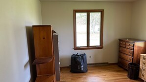 A room with wooden flooring, a window, a dresser, and a bag on the floor. - NFL ready 30 min from stadium Charming 3-bedroom bungalow Harrison City (harrison city)