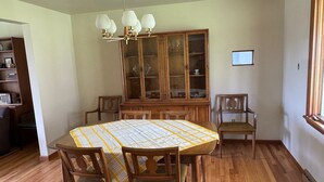 A dining room with a wooden table, chairs, a chandelier, a wooden cabinet, and a window. - NFL ready 30 min from stadium Charming 3-bedroom bungalow Harrison City (harrison city)