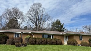 A two-story house with a brick exterior, a front porch, and a well-maintained lawn. - NFL ready 30 min from stadium Charming 3-bedroom bungalow Harrison City (harrison city)