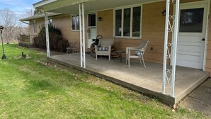 A house with a covered porch, a chair, a table, and a door. - NFL ready 30 min from stadium Charming 3-bedroom bungalow Harrison City (harrison city)