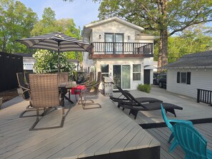 Eine Terrasse mit Gartenmöbeln, ein überdachter Sitzbereich und ein zweistöckiges Haus im Hintergrund.