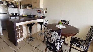 Una cocina moderna con una isla central, taburetes de bar y una mesa de comedor con sillas.
