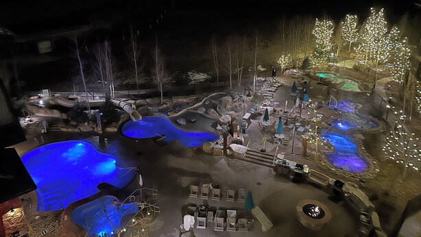 Een buitengebied van een resort met een jacuzzi, zitgedeeltes en een zwembad met blauwe verlichting.