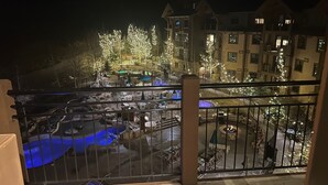 Een uitzicht op een hotel binnenplaats 's nachts, met een zwembad, terras en een groot gebouw met veel ramen.