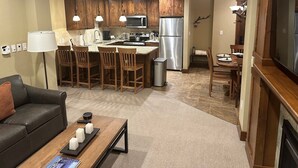Een moderne keuken met houten kastjes, roestvrijstalen apparatuur en een eethoek met een tafel en stoelen.