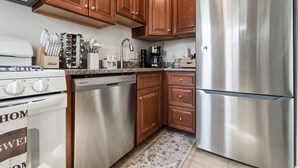 A kitchen with wooden cabinets, stainless steel appliances, and a granite countertop. - Stylish 3-bedroom Escape in charming Alexandria 5 Min to Old Town, Metro Nearby (Alexandria)