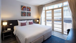 A hotel room with a large bed, two bedside tables, a desk, and a large window with curtains. - 24 Inn at BTS Phrom Phong (Bangkok)
